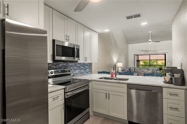 kitchen with ceiling fan, sink, stainless steel appliances, kitchen peninsula, and light hardwood / wood-style floors