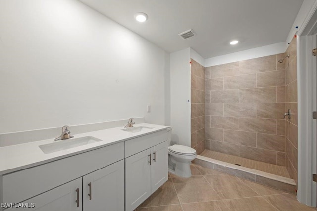 bathroom with tile patterned flooring, a tile shower, vanity, and toilet