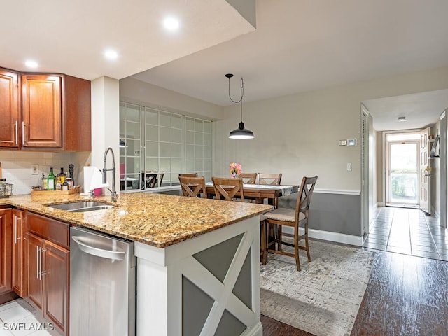 kitchen featuring pendant lighting, backsplash, light stone counters, and sink