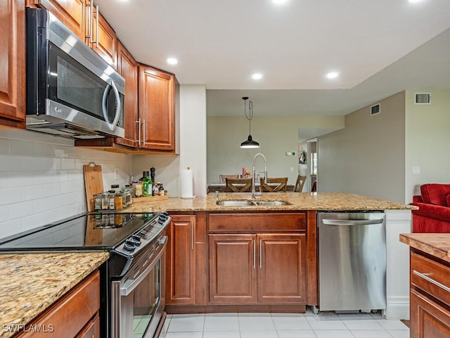 kitchen with appliances with stainless steel finishes, tasteful backsplash, sink, light tile patterned floors, and decorative light fixtures