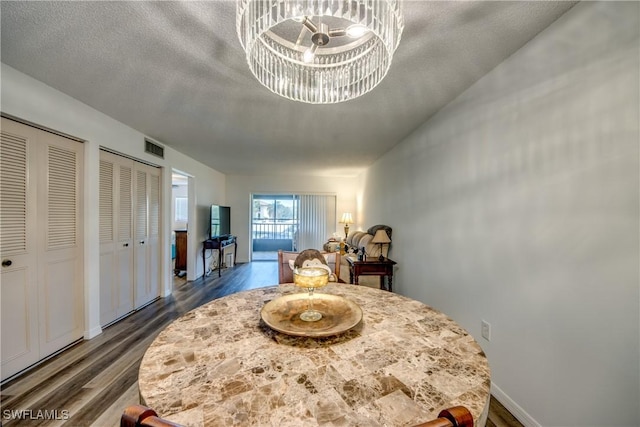 interior space featuring dark hardwood / wood-style floors, two closets, a textured ceiling, and a chandelier