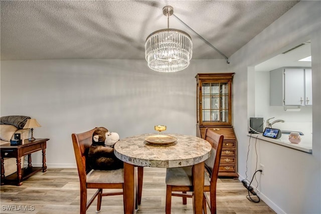 dining area featuring sink, light wood-type flooring, and a notable chandelier