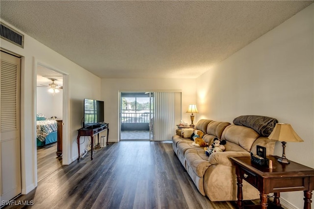 living room with ceiling fan, dark hardwood / wood-style floors, and a textured ceiling