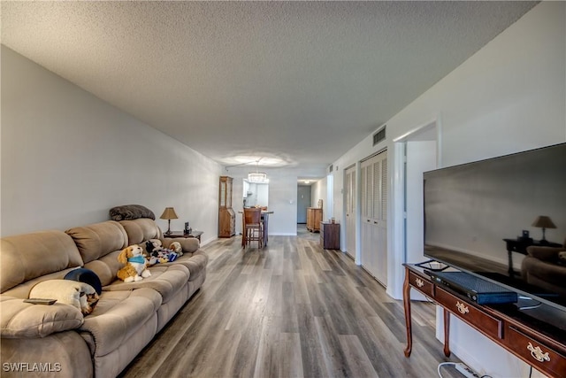 living room with wood-type flooring, a textured ceiling, and a notable chandelier