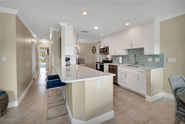 kitchen featuring a kitchen bar, stainless steel appliances, sink, white cabinetry, and light tile patterned flooring