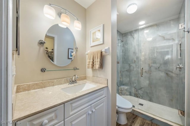 full bath featuring toilet, a shower stall, wood finished floors, and vanity