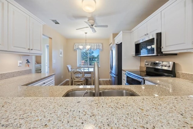 kitchen featuring visible vents, white cabinets, light stone counters, stainless steel appliances, and a sink