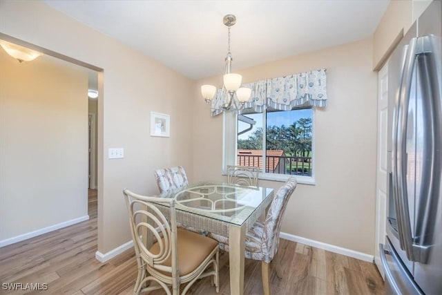 dining room featuring a notable chandelier, wood finished floors, and baseboards