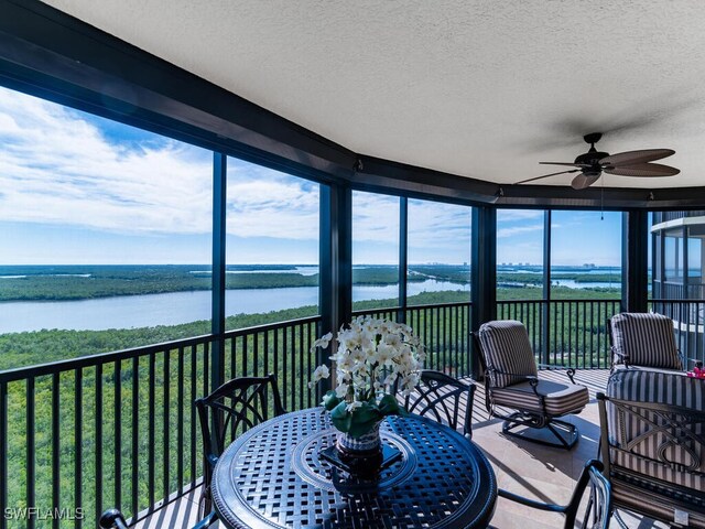 sunroom / solarium with a water view and ceiling fan