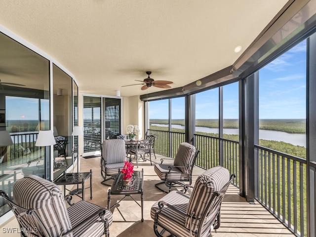 sunroom / solarium featuring ceiling fan and a water view