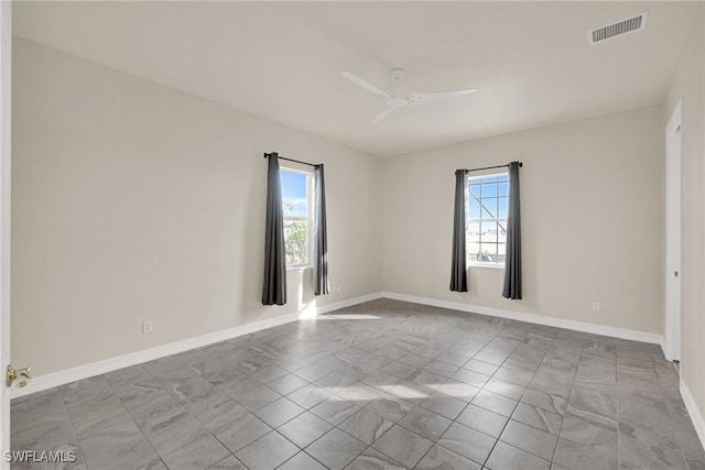 empty room featuring ceiling fan and a wealth of natural light