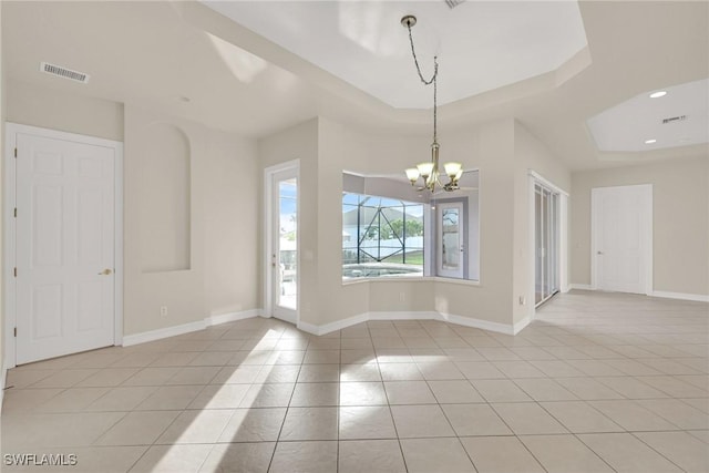 spare room with light tile patterned floors, an inviting chandelier, and a tray ceiling