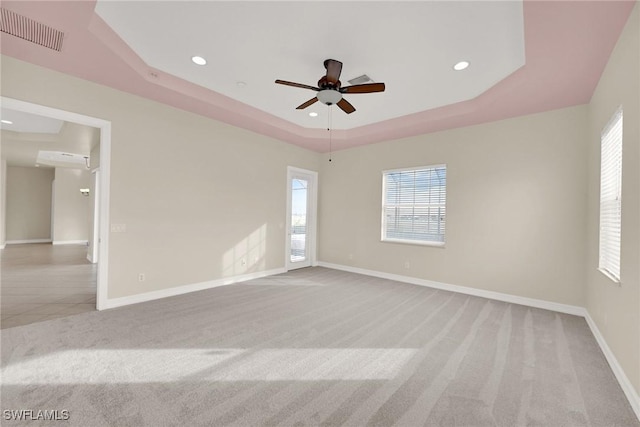 carpeted empty room with ceiling fan and a tray ceiling