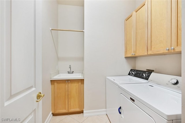 laundry area with washer and clothes dryer, sink, light tile patterned floors, and cabinets