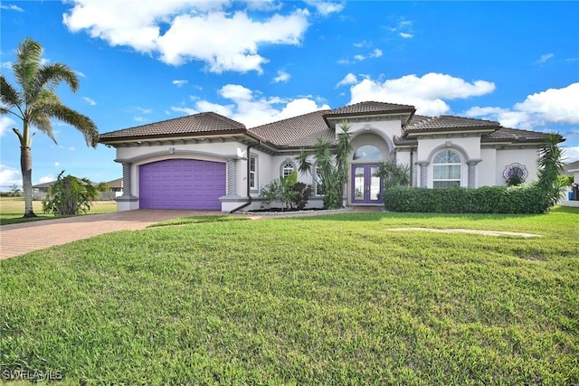 mediterranean / spanish house with a garage, a front lawn, and french doors