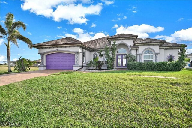 mediterranean / spanish house with decorative driveway, french doors, a garage, and stucco siding