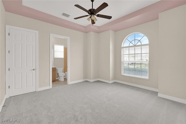 unfurnished room featuring ceiling fan, light colored carpet, and a tray ceiling