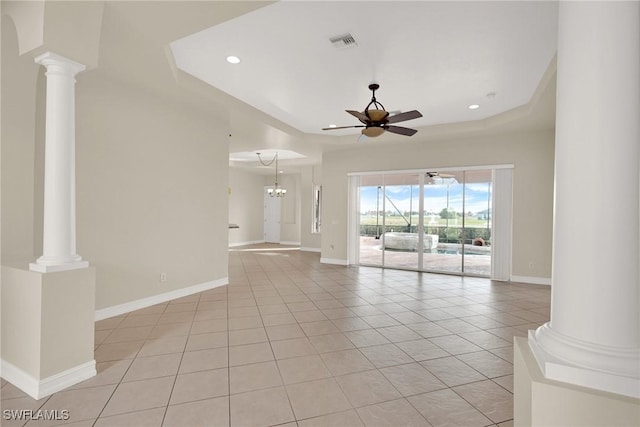 unfurnished living room featuring a raised ceiling, light tile patterned floors, ceiling fan with notable chandelier, and ornate columns