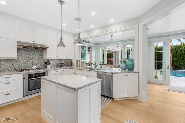 kitchen with white cabinetry, a center island, light hardwood / wood-style floors, decorative light fixtures, and appliances with stainless steel finishes