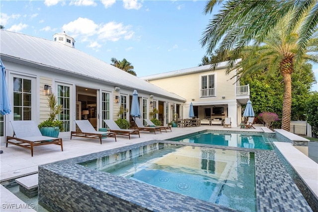 back of house with a swimming pool with hot tub and a patio