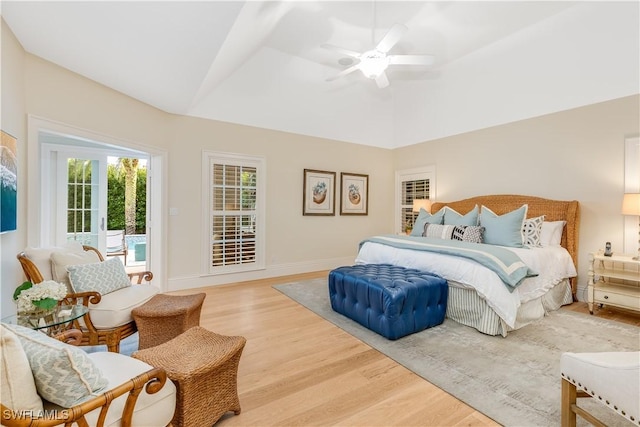 bedroom featuring lofted ceiling, a raised ceiling, ceiling fan, access to exterior, and wood-type flooring