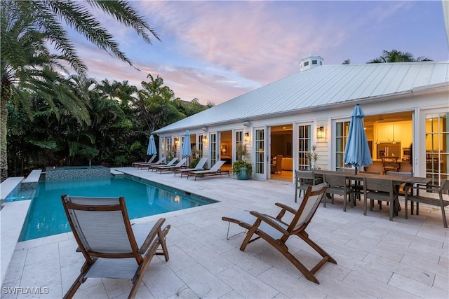 pool at dusk featuring a patio area