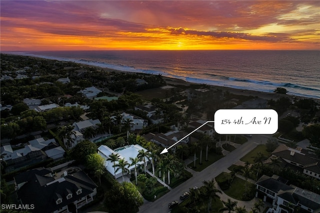 aerial view at dusk with a water view and a view of the beach