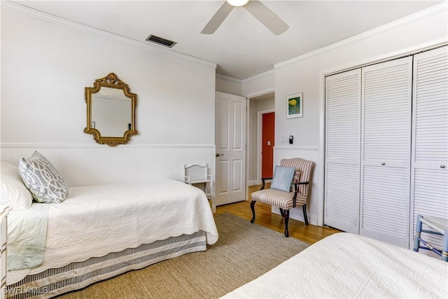 bedroom with crown molding, ceiling fan, a closet, and light hardwood / wood-style floors