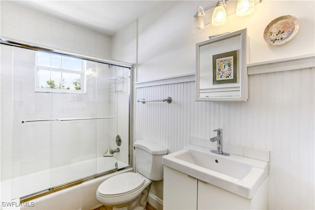 full bathroom with shower / bath combination with glass door, wood walls, sink, and toilet