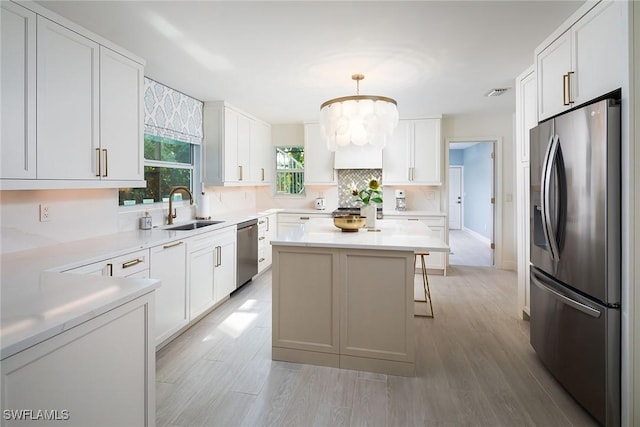 kitchen featuring stainless steel appliances, sink, pendant lighting, and white cabinets