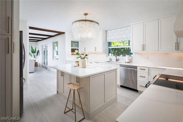 kitchen with a sink, stainless steel appliances, a center island, and light countertops