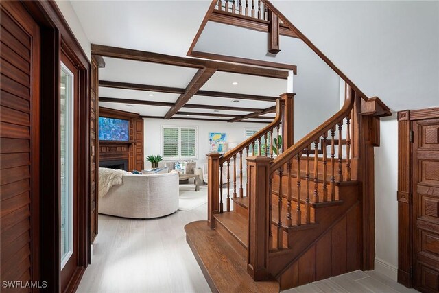 staircase with wood finished floors, coffered ceiling, recessed lighting, a fireplace, and beamed ceiling