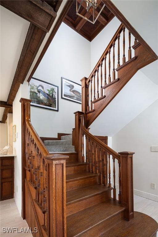 stairway with beam ceiling and baseboards