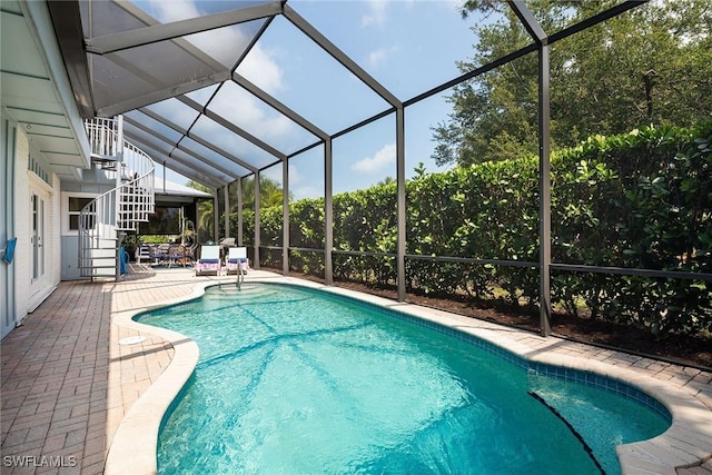 outdoor pool with a lanai, stairway, and a patio