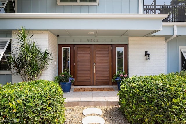 entrance to property featuring board and batten siding, a balcony, and brick siding