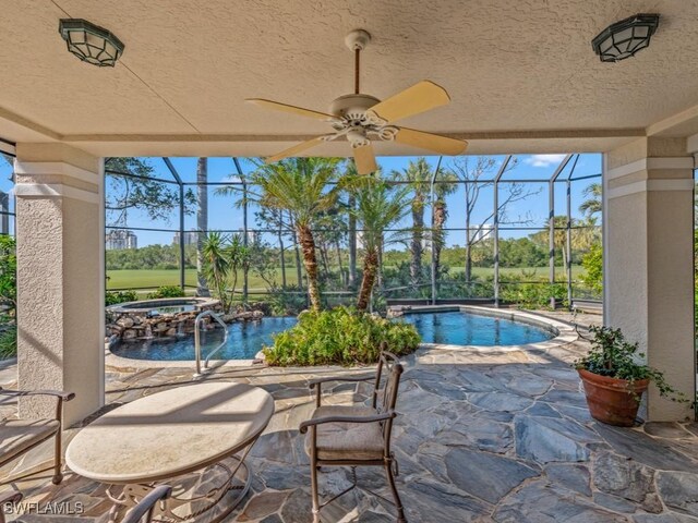 view of swimming pool featuring glass enclosure, an in ground hot tub, ceiling fan, and a patio