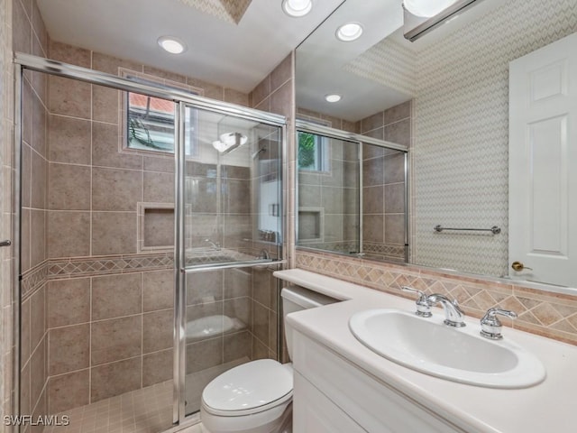 bathroom with vanity, toilet, decorative backsplash, and walk in shower