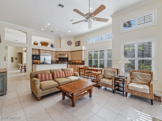 tiled living room with a towering ceiling, ceiling fan, and crown molding