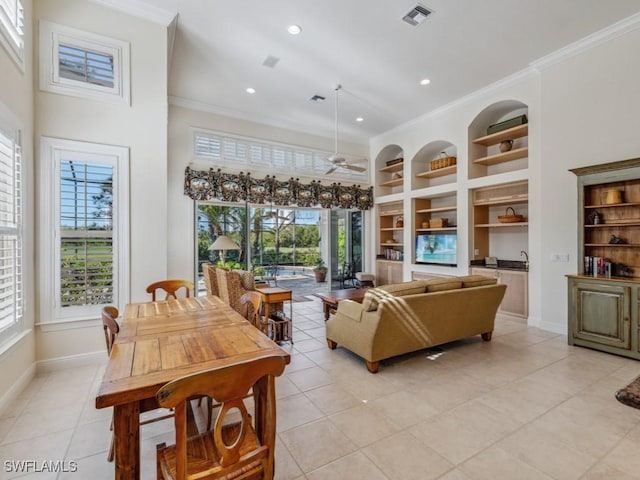 tiled living room featuring ceiling fan, built in features, and crown molding