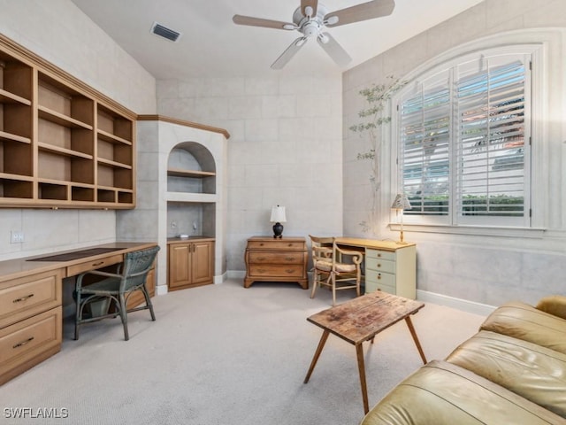 home office with built in desk, light colored carpet, and ceiling fan