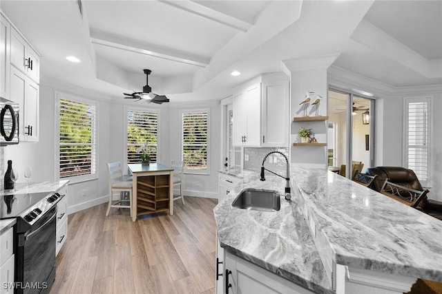 kitchen with a raised ceiling, white cabinetry, sink, and black range with electric cooktop