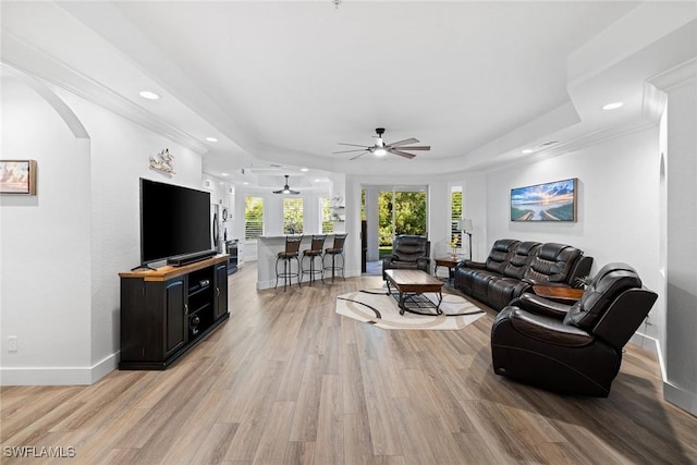 living room featuring a tray ceiling, light hardwood / wood-style flooring, ceiling fan, and crown molding