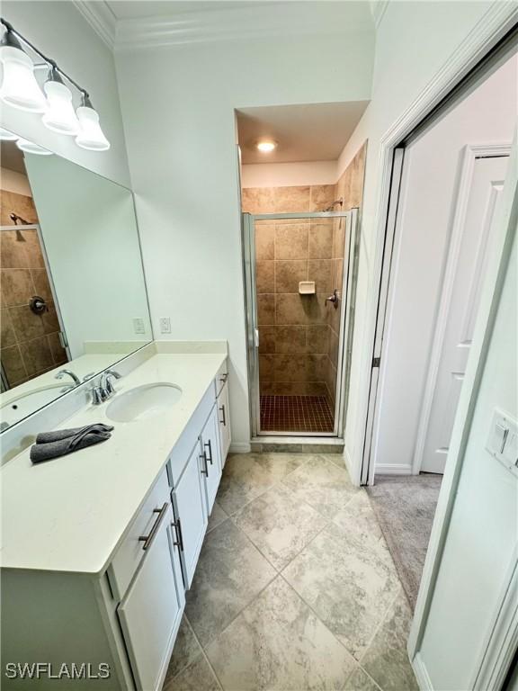 bathroom with vanity, a shower with door, and ornamental molding