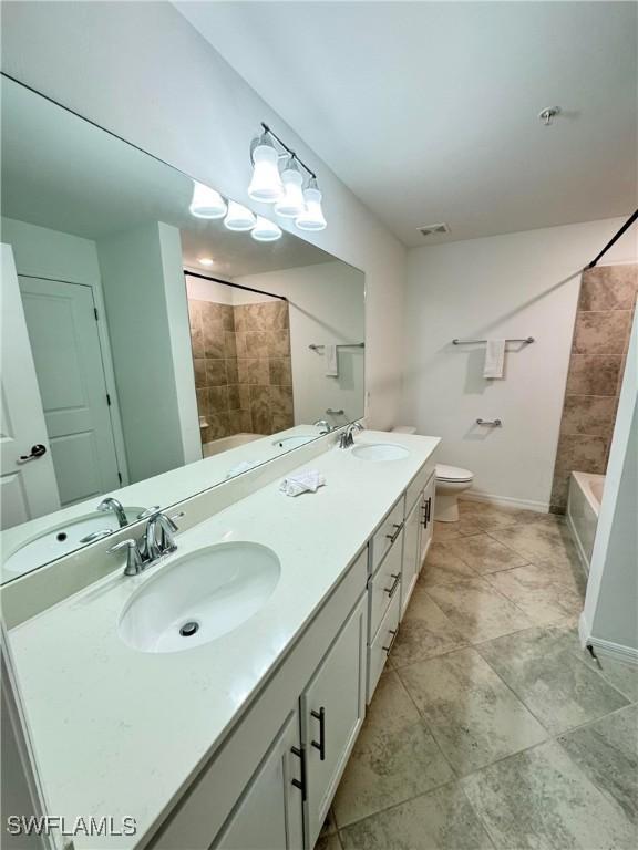 full bathroom featuring vanity, tiled shower / bath combo, and toilet