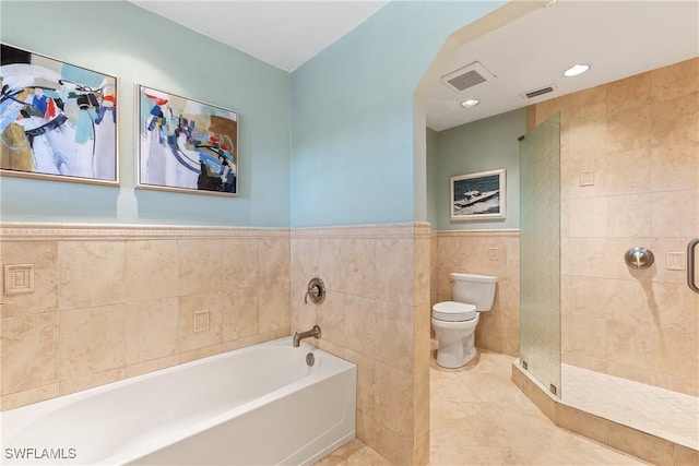 bathroom with tile patterned floors, shower with separate bathtub, toilet, and tile walls