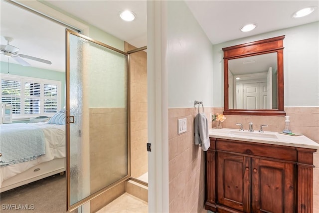 bathroom with vanity, tile patterned flooring, ceiling fan, tile walls, and an enclosed shower