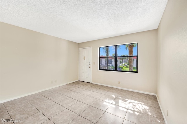 spare room with light tile patterned flooring and a textured ceiling