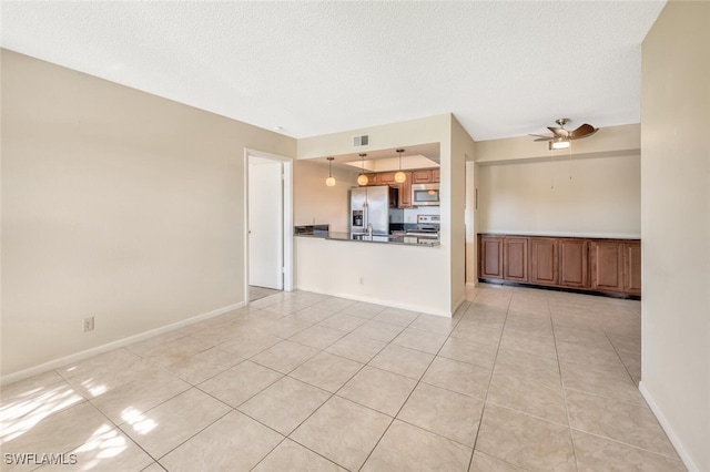 unfurnished living room featuring ceiling fan, light tile patterned flooring, and a textured ceiling