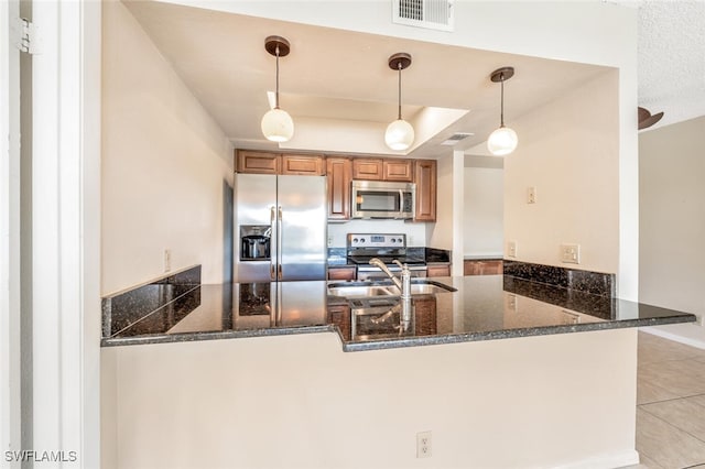 kitchen with sink, dark stone countertops, decorative light fixtures, kitchen peninsula, and stainless steel appliances