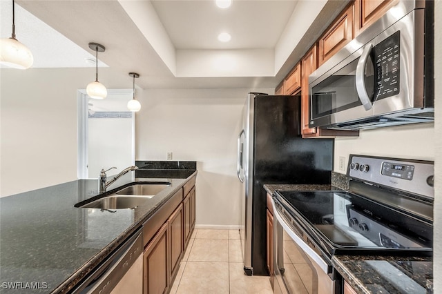 kitchen with appliances with stainless steel finishes, dark stone counters, sink, pendant lighting, and light tile patterned flooring